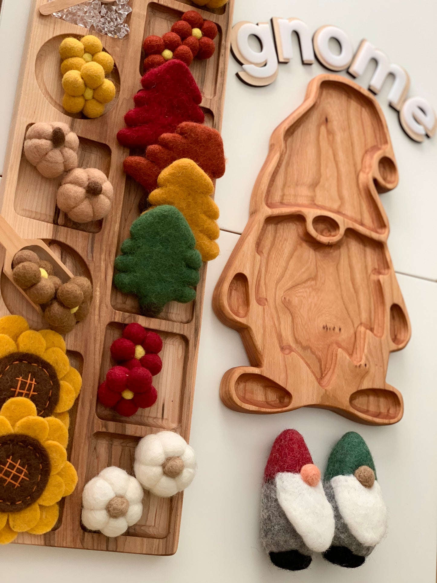 Natural wooden gnome-shaped sensory tray with colorful felt play food and decorative letters spelling gnome on white background