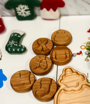 Round wooden cookie stamps with various holiday designs on a white surface with felt holiday decorations nearby