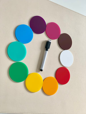 Ten colorful circular discs arranged in a ring around a black and white marker on a beige surface
