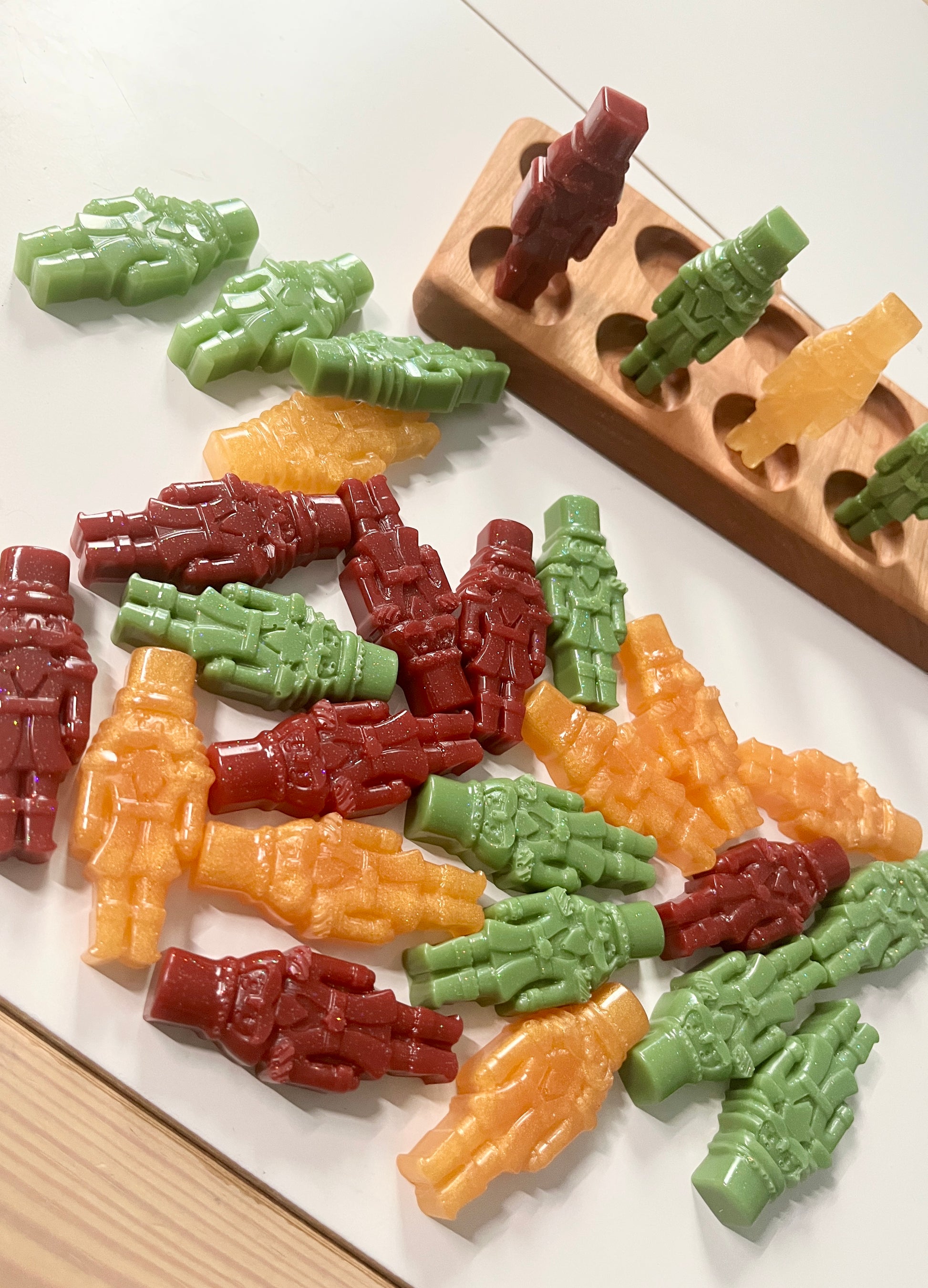 Colorful resin gingerbread on a white surface with a wooden ten frame in the background.