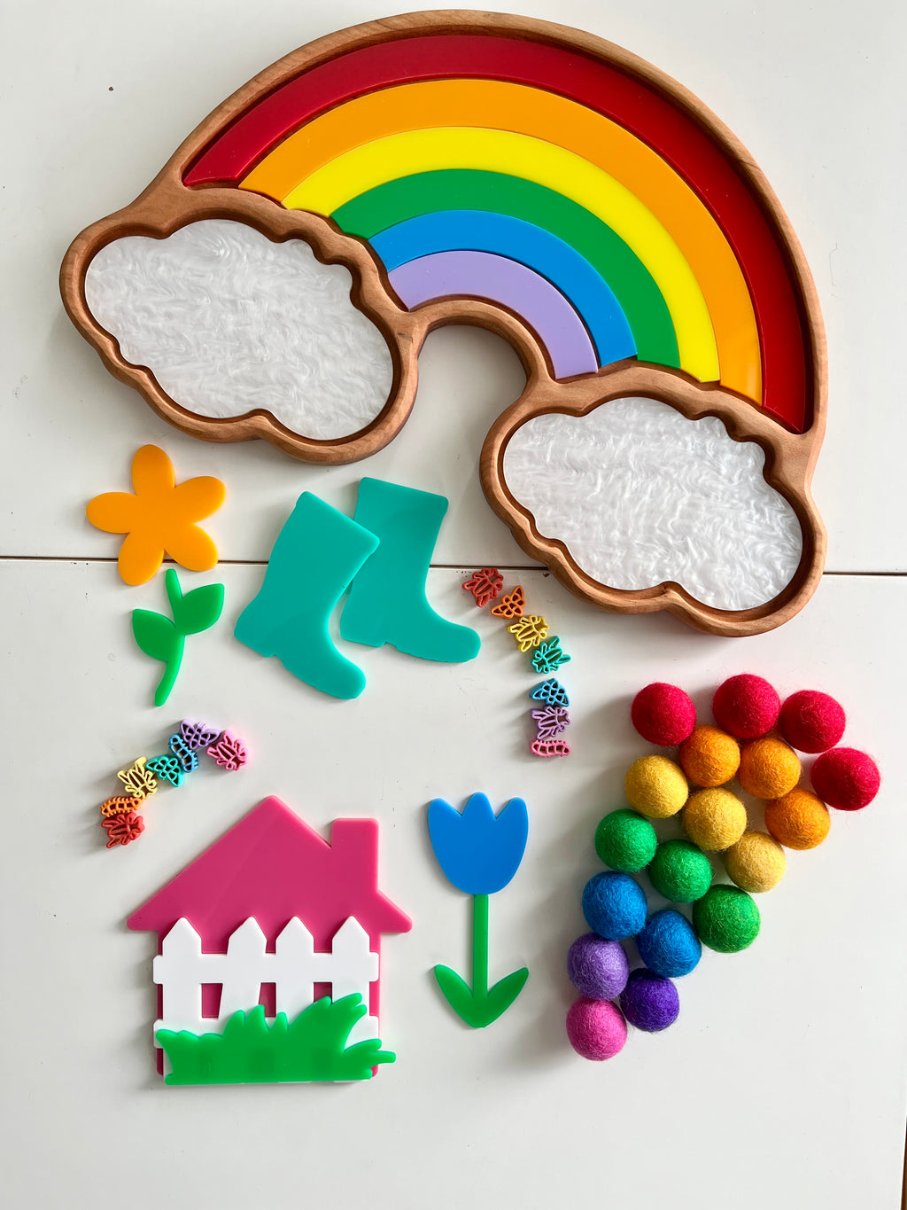 Wooden rainbow tray with colorful arch pieces, textured white cloud sections, and assorted colorful shapes on white surface