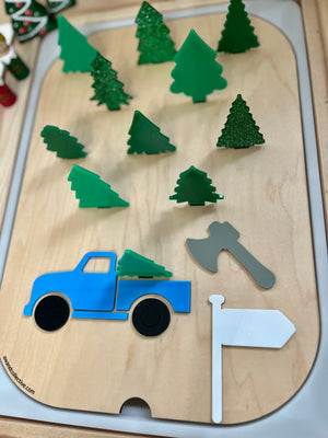Wooden activity board with green tree shapes, blue truck, gray axe, and white flag on a light wood background