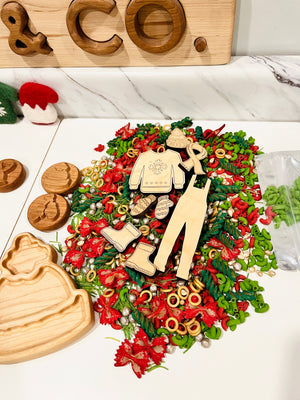 Assortment of colorful pasta shapes with wooden cutouts of winter clothing and accessories on a white surface