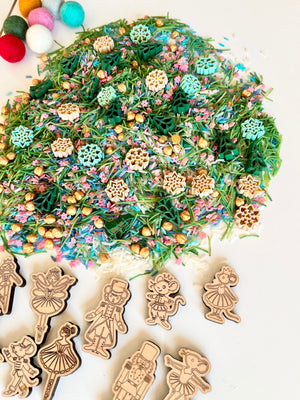 Pile of colorful festive rice and beads with wooden holiday-themed character cutouts on white surface