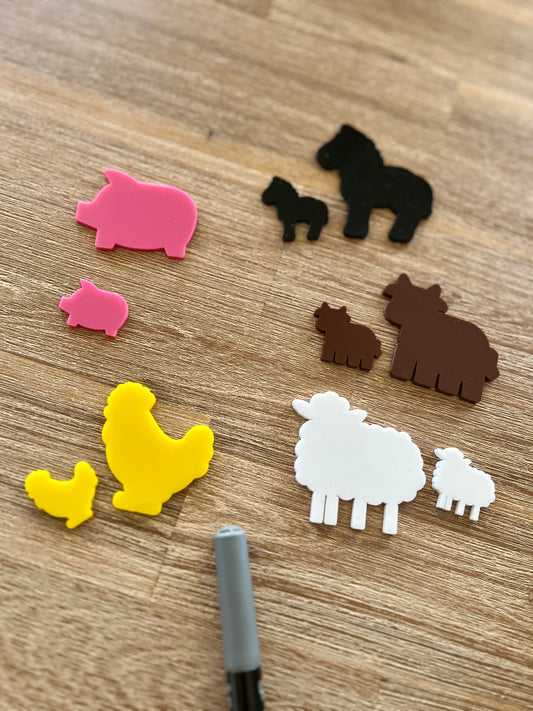 Colorful parent and child farm animal shapes including pigs, horses, cows, chickens, and sheep paired by size on a wood surface, Little Dry Erasables - Farm Animal Parent & Kids, handcrafted, homeschool, education resources.