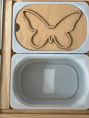 Small butterfly-shaped wooden Flisat table top insert with white plastic bin in wooden frame on light surface