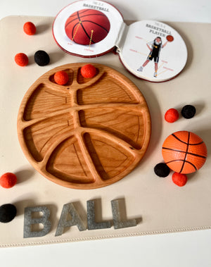 Wooden serving tray carved with basketball lines surrounded by small felt balls, a mini basketball, and metal letters spelling BALL