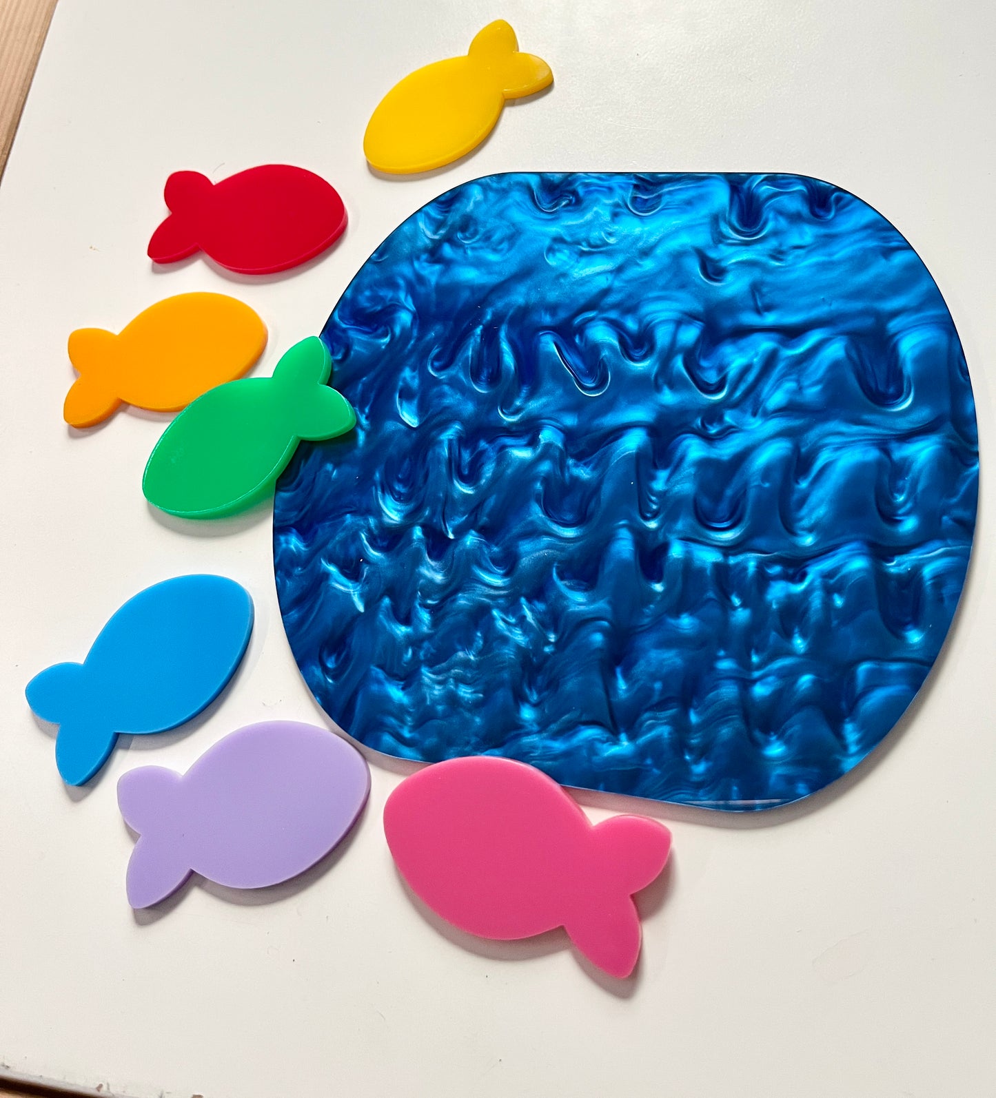 Colorful dry erase fish around a marble dry erase pond on a white background