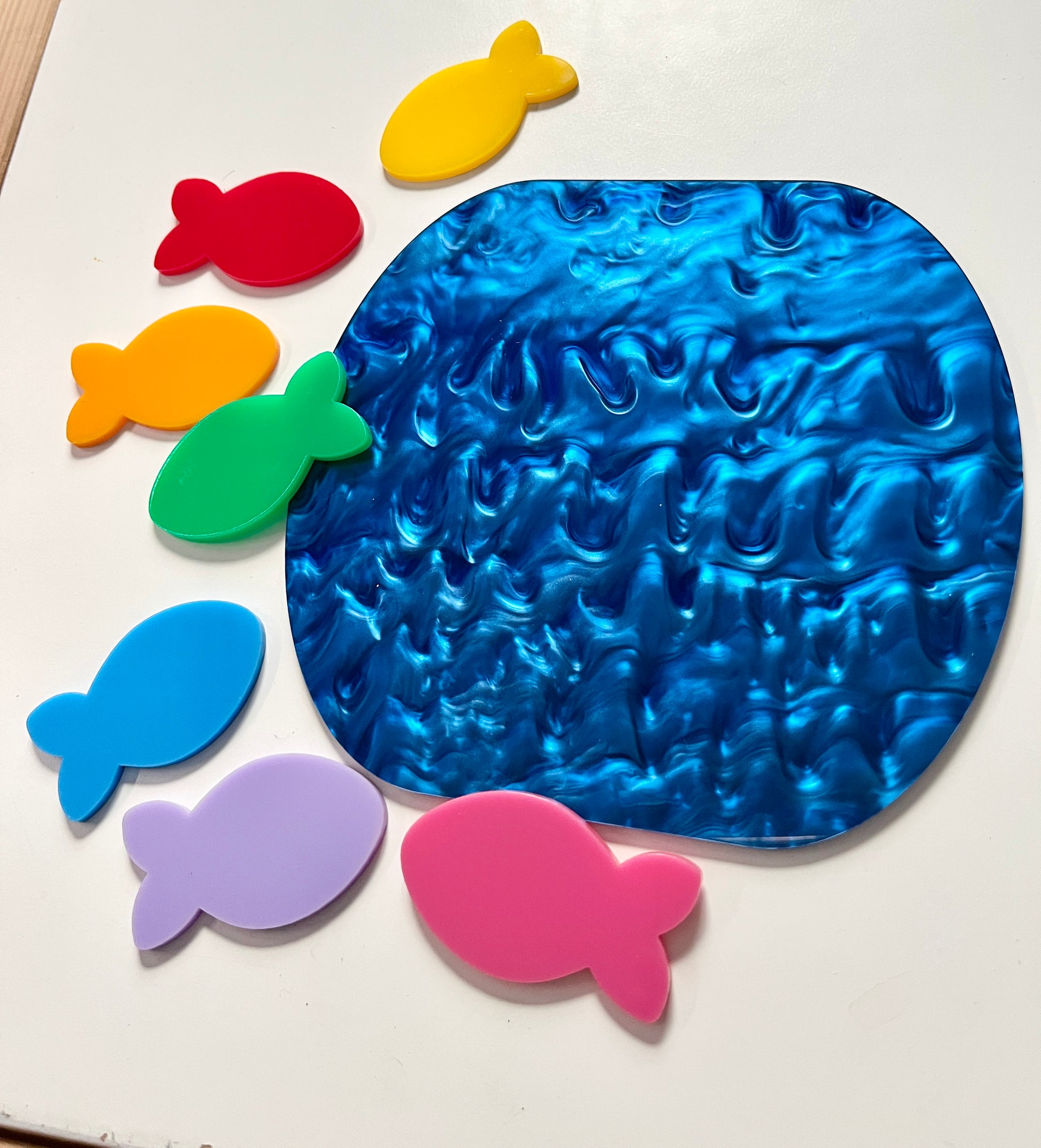Colorful dry erase fish around a marble dry erase pond on a white background