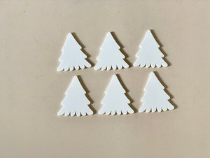 Set of six white pine tree-shaped dry erasable wooden pieces on beige surface with smooth finish