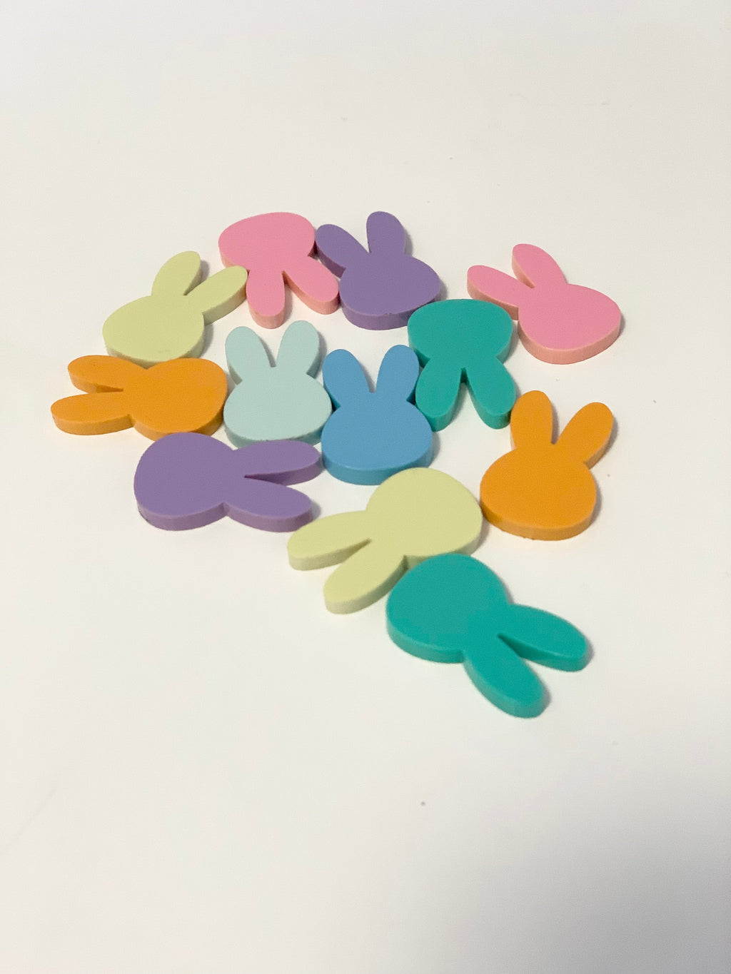 Colorful wooden bunny-shaped tokens arranged in a circular pattern on a white surface