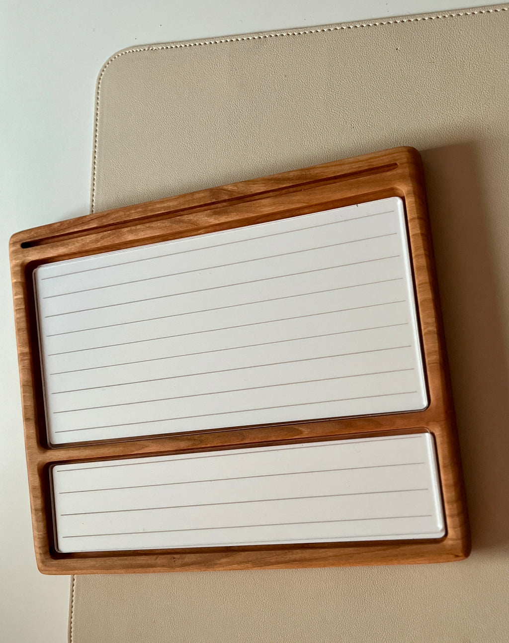 Smaller wooden multipurpose sensory tray with two lined white dry erase inserts and groove for marker on beige surface