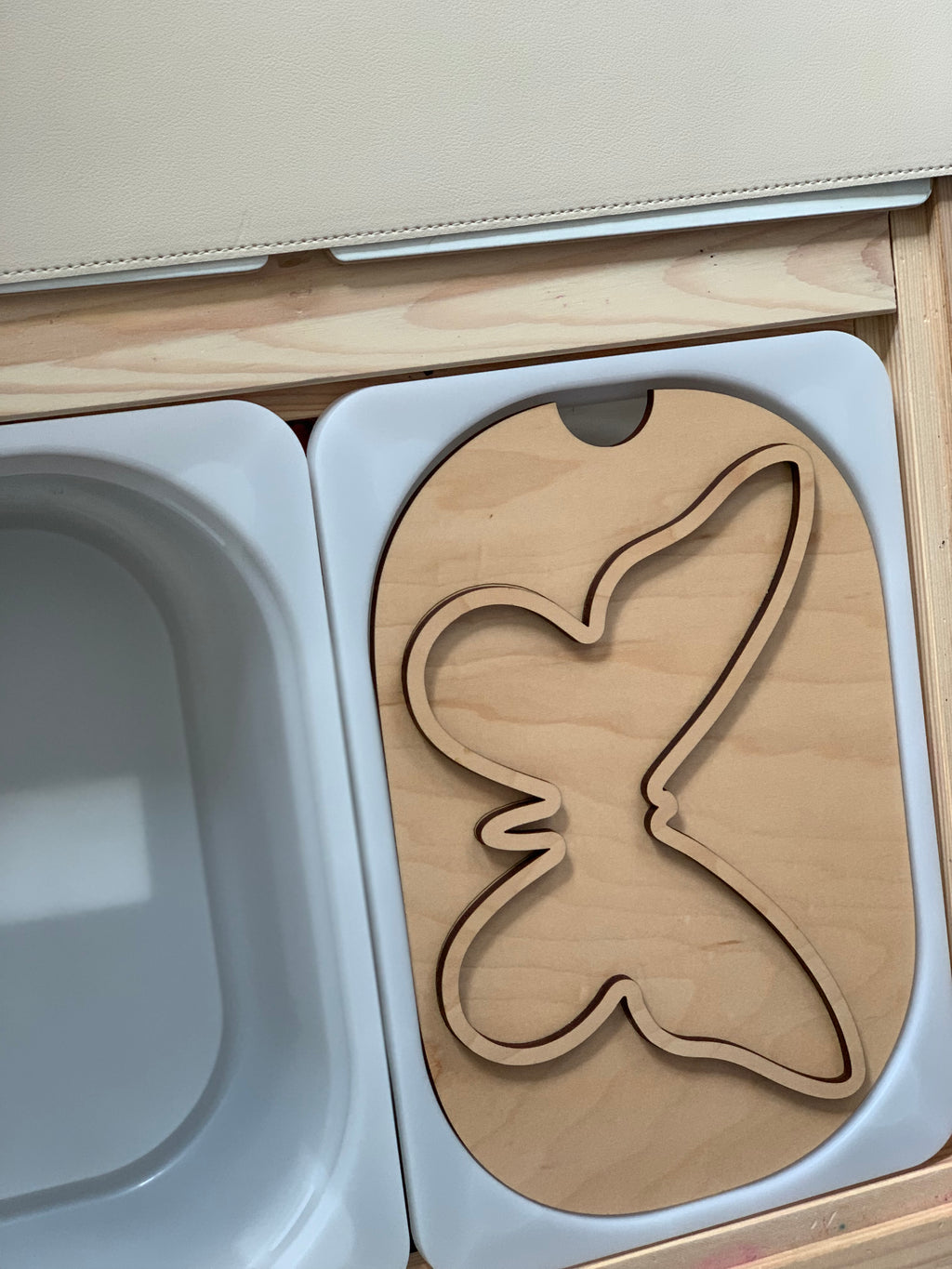 Small butterfly-shaped wooden insert made of maple plywood fitting inside a white Flisat bin tray