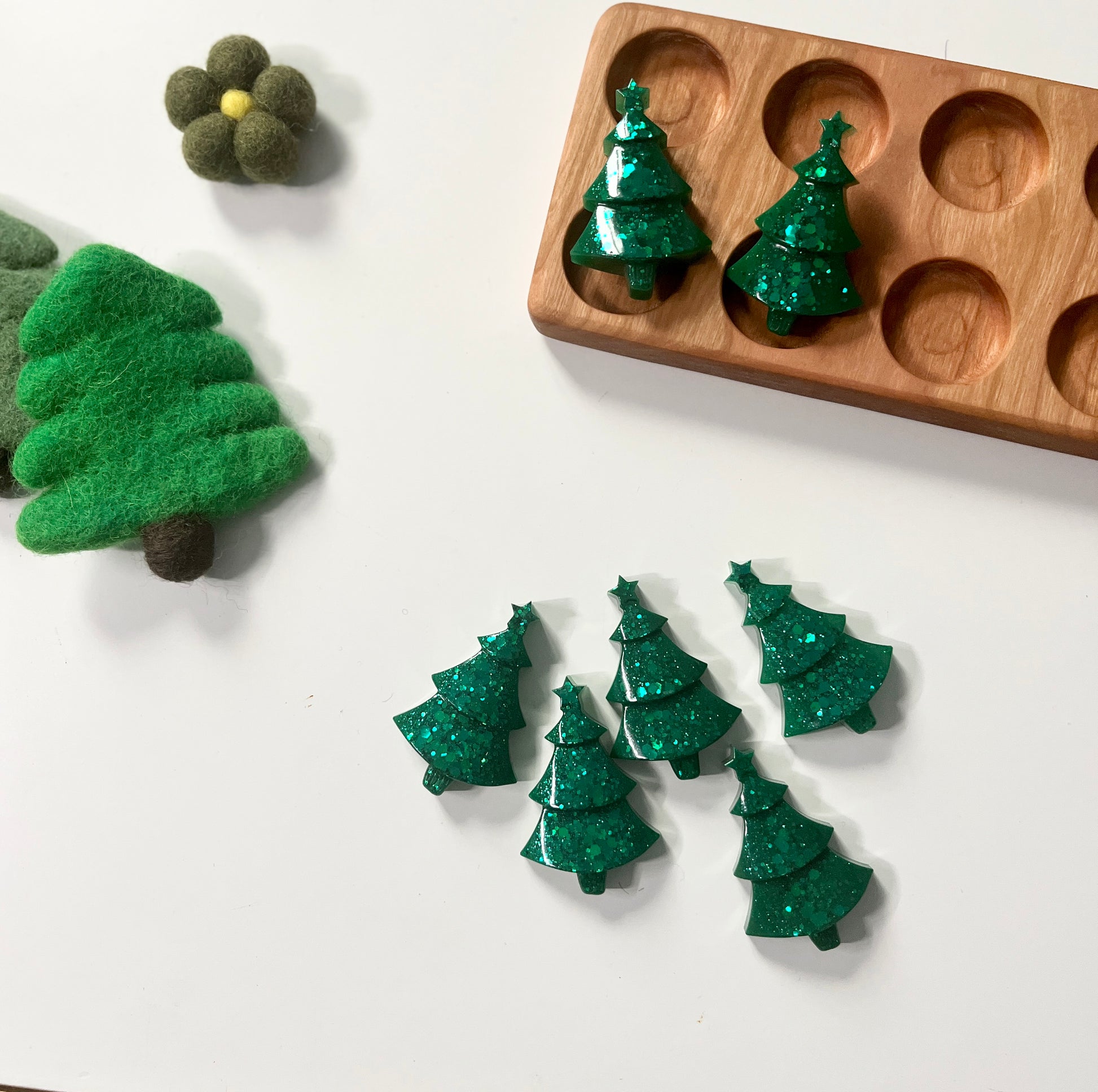 Green Christmas Tree shaped resin toys on a white surface with a wooden ten frame