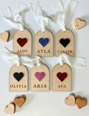 Set of six wooden gift tags with glittery and solid heart shapes and engraved names tied with white fabric ribbons