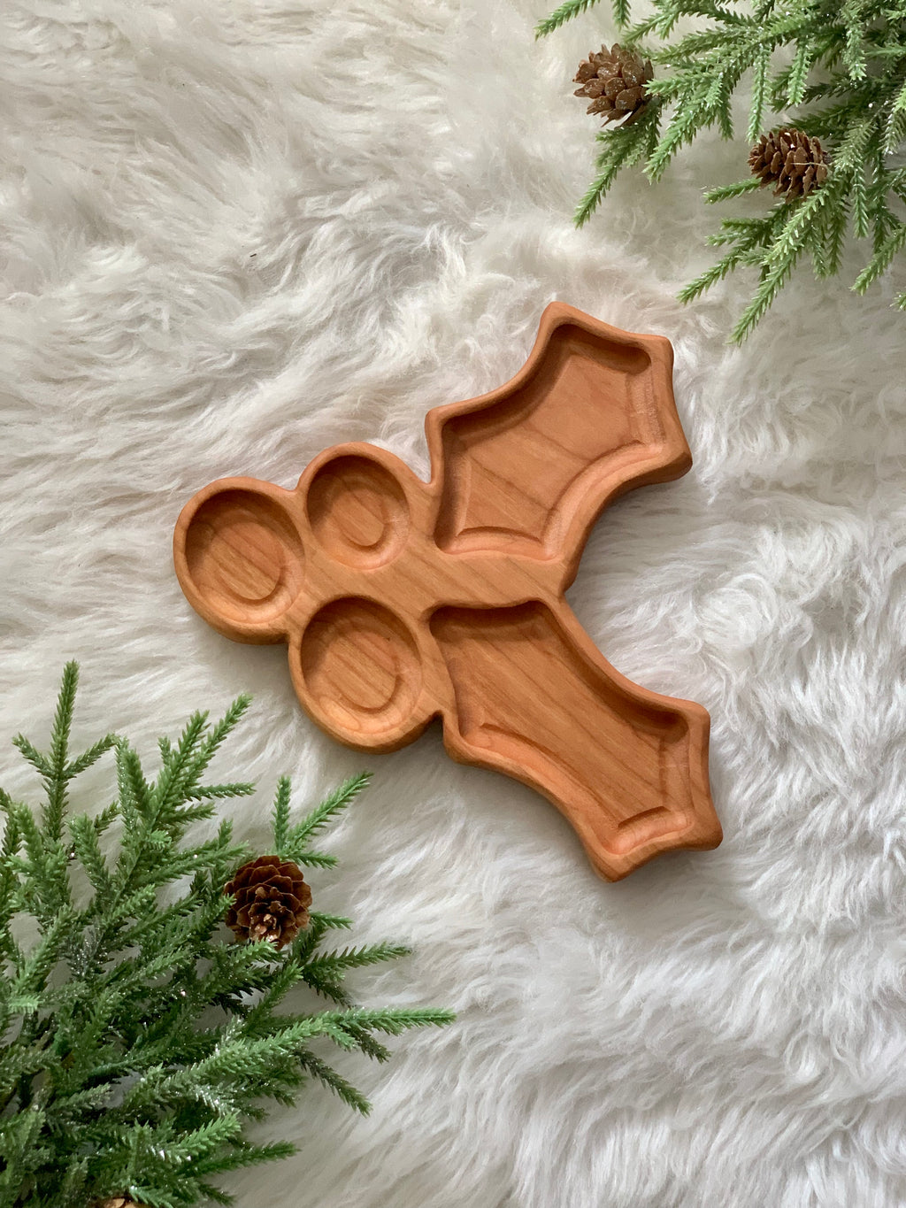 Wooden holly-shaped sensory tray with three berry and two leaf compartments on soft white textured surface