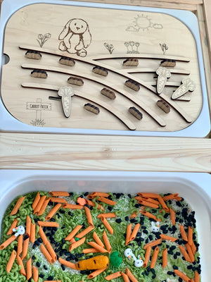 Wooden puzzle board with carved bunny, flowers, and carrot shapes above a sensory bin filled with colorful pasta and beans