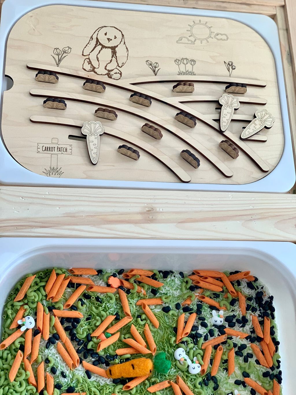 Wooden puzzle board with carved bunny, flowers, and carrot shapes above a sensory bin filled with colorful pasta and beans