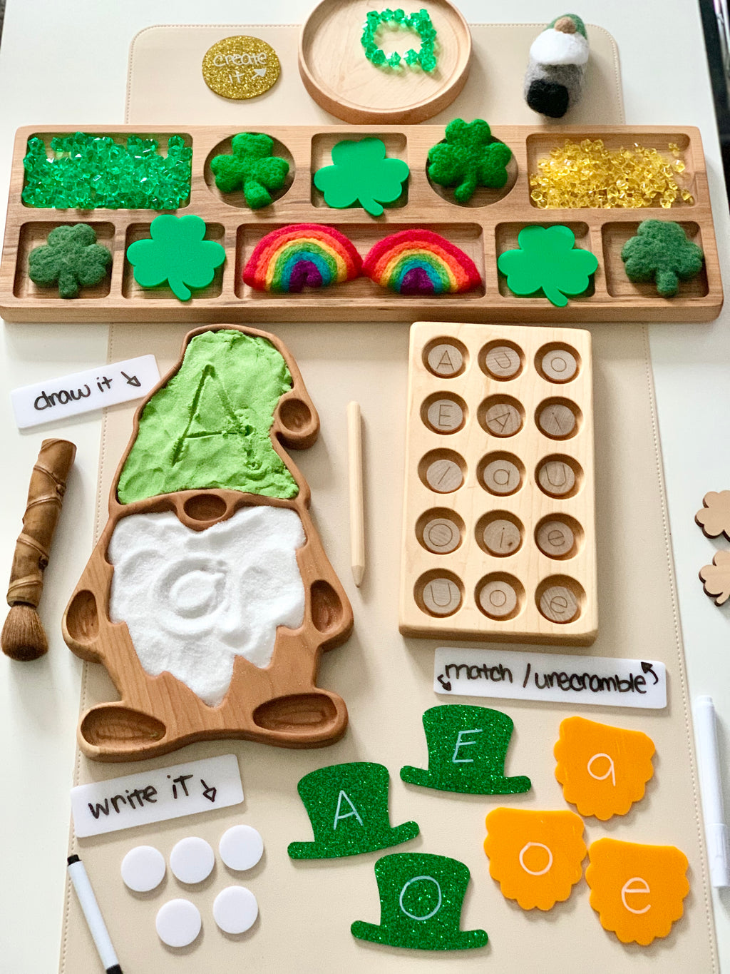 Wooden gnome-shaped tray with green felt hat, white beard, letter tiles, shamrocks, rainbows, and learning activity pieces on white mat