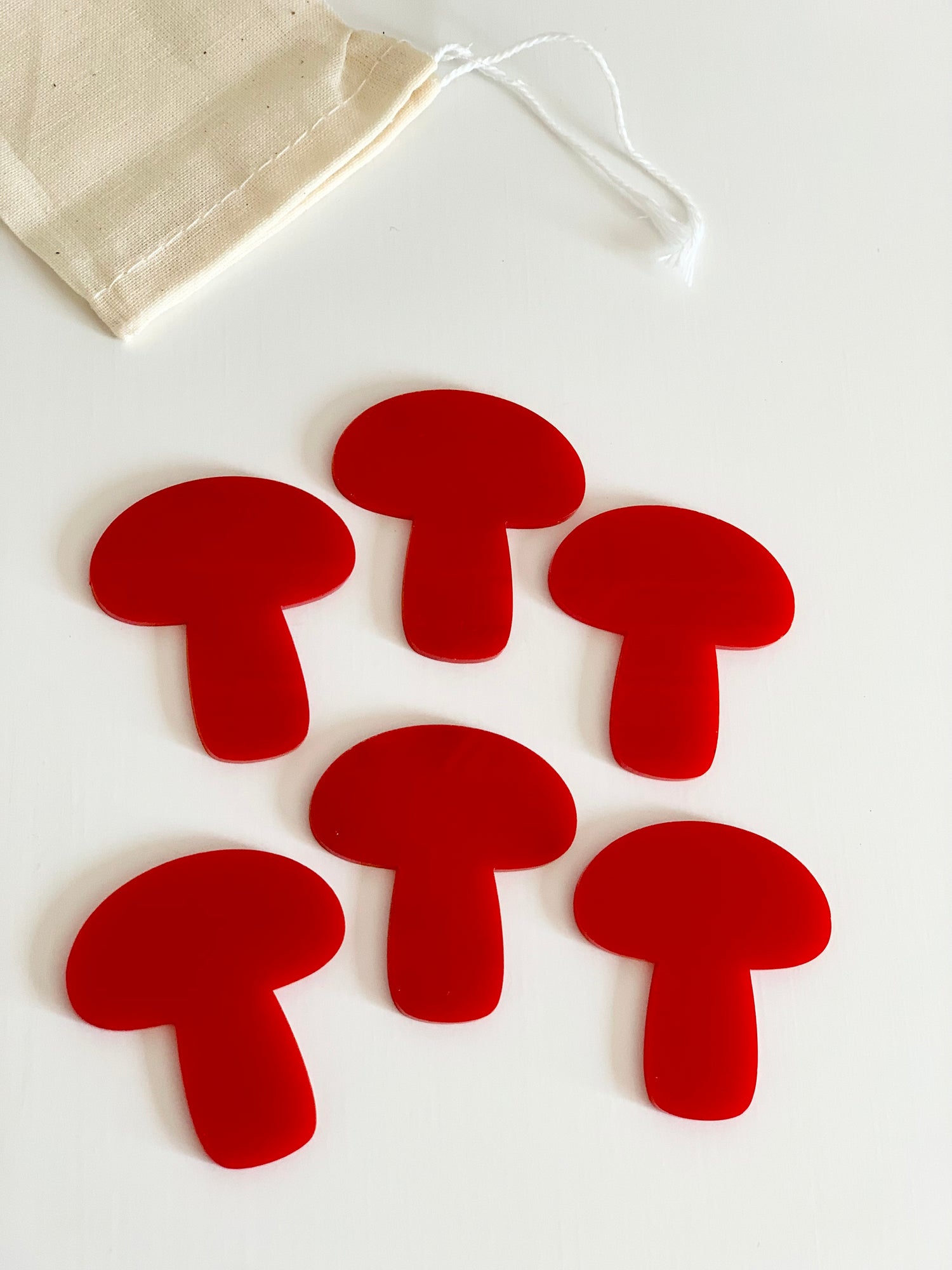Set of six red mushroom-shaped dry erase boards with a beige drawstring pouch on white background