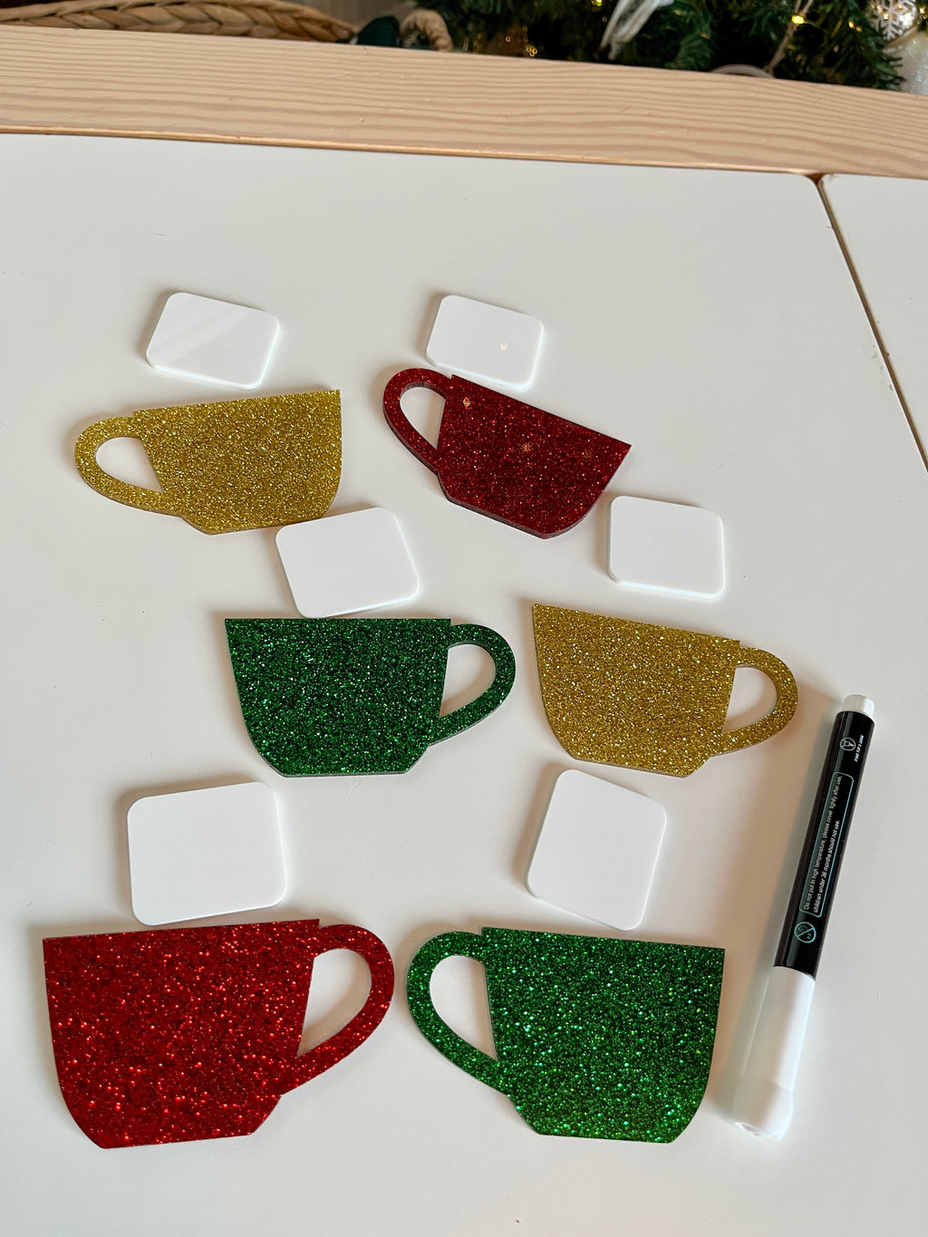 Set of six Christmas glitter mugs and marshmallows dry erasable shapes with a marker on white surface