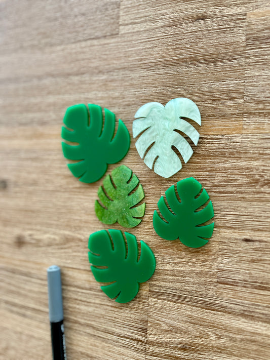 Five handcrafted tropical leaf shapes in varying shades of green arranged on a wooden surface with a black marker, Little Dry Erasables - Tropical Leaves, homeschool, education resources.