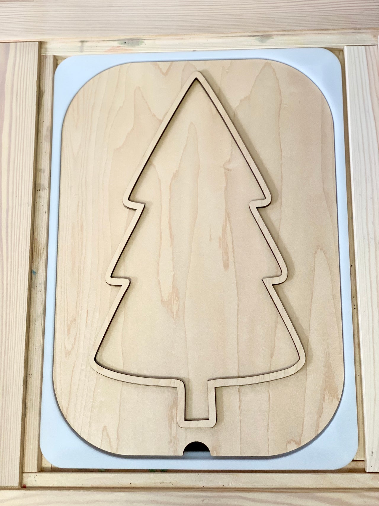 Unfinished light wood puzzle board with a large Christmas tree shape cutout and smooth rounded edges