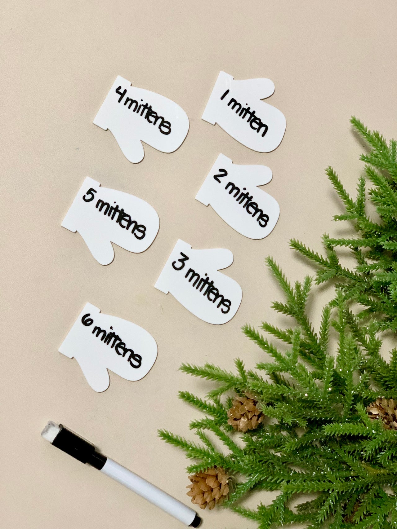 Set of six white dry erasable mitten-shaped flashcards numbered one to six with black dry erase marker and pine branch decor