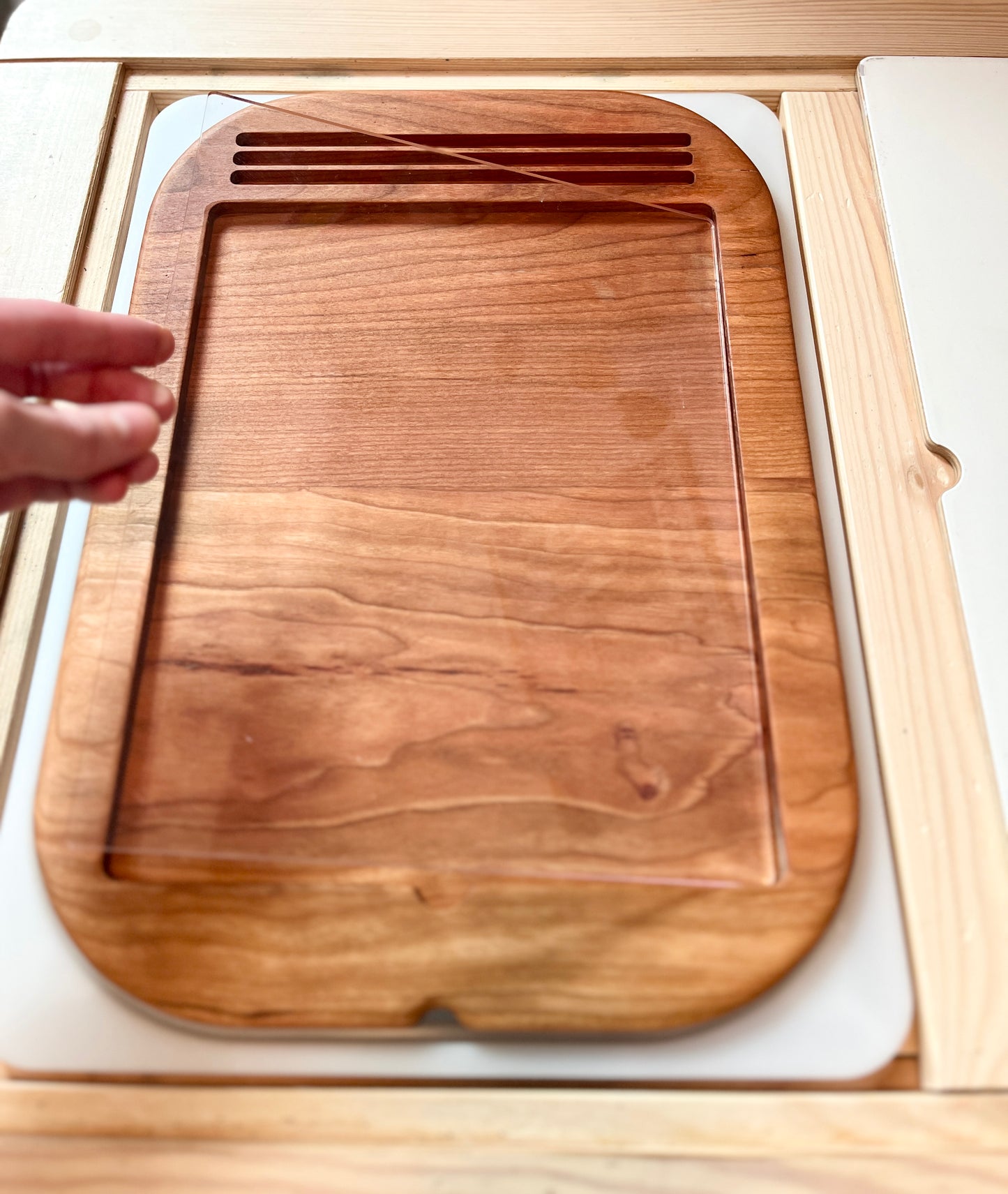Wooden dry erase tracing board with a hand holding the dry erase board above the wooden tray holder. 