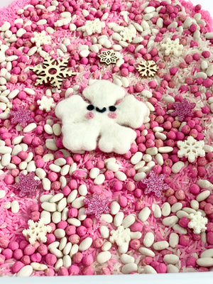 Pink and white sensory filler with felt snowflake, wooden snowflakes, glitter stars, and rice on white tray