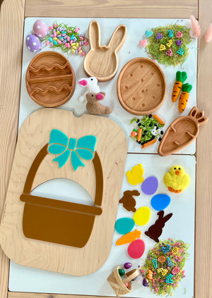 Wooden trays shaped like Easter eggs, bunny, and carrot with colorful felt and plastic Easter decorations on a table