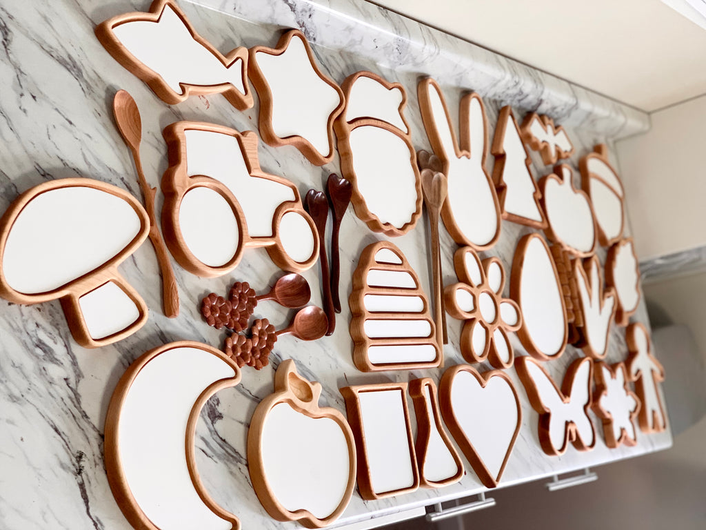 Wooden cat-shaped sensory tray with various shaped compartments and natural wood spoons on marble surface