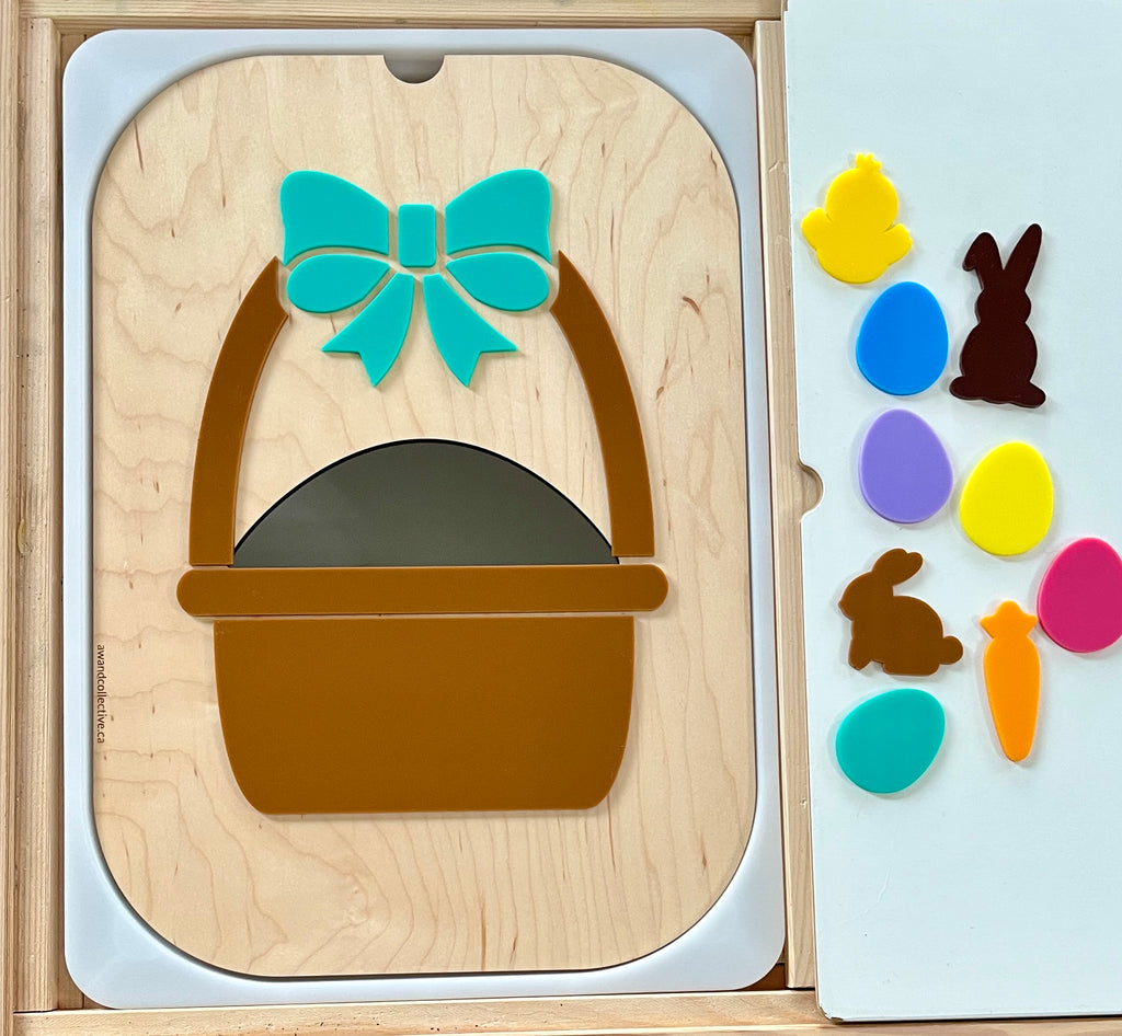 Wooden board with a brown basket and teal bow shape pieces next to colorful Easter-themed cutouts on a white surface