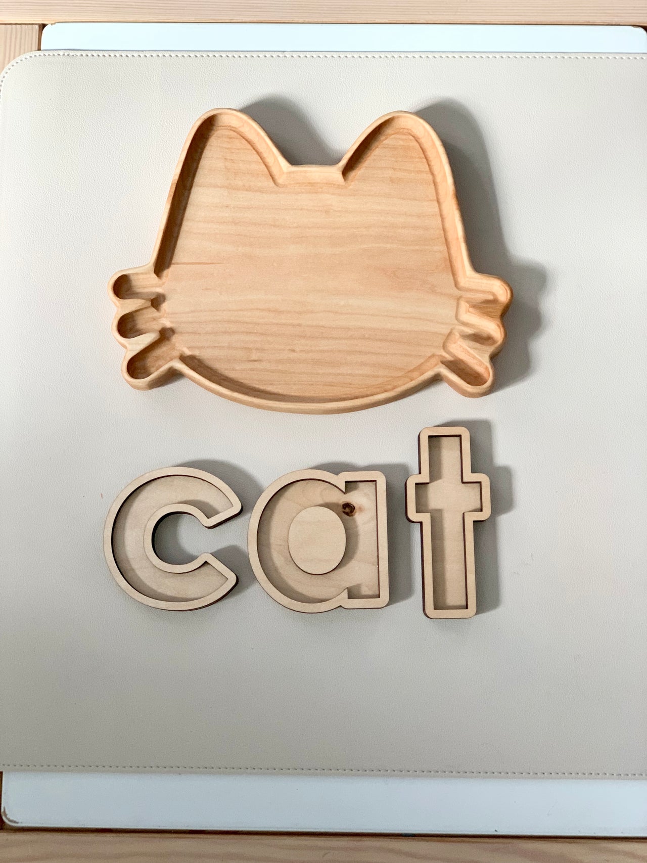 Wooden cat-shaped sensory tray with matching wooden letters c, a, t on white background