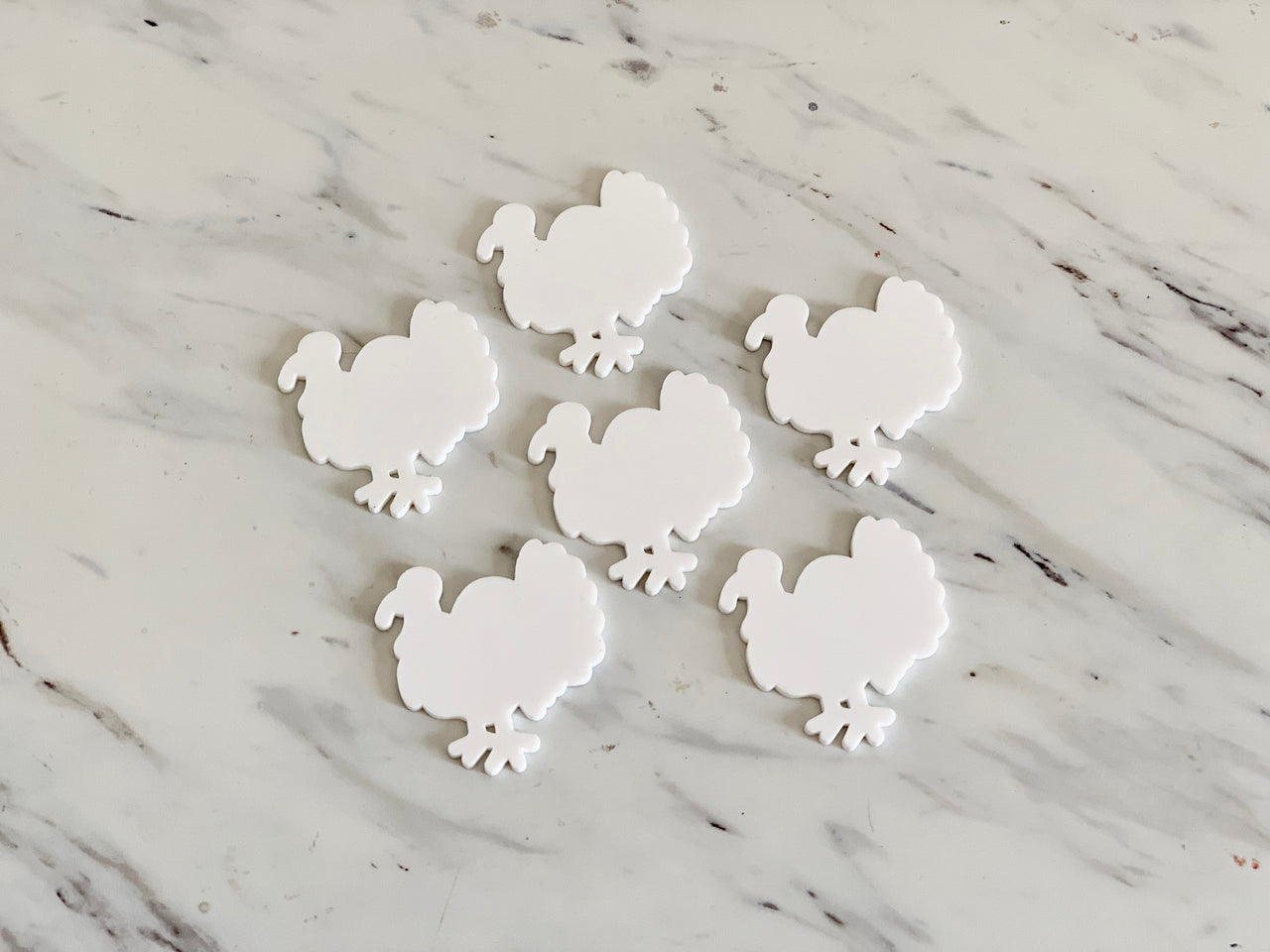 Set of six white turkey-shaped dry erase boards on a white marble surface with faint gray veining
