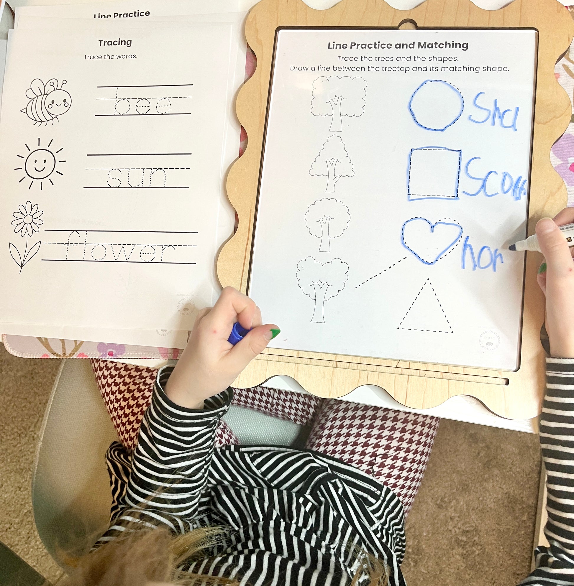 Child's hand tracing on a worksheet with educational content