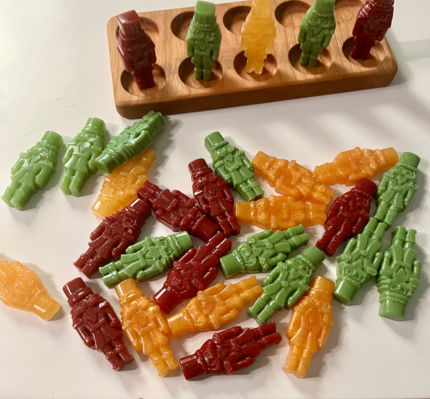 Colorful resin gingerbread on a white surface with a wooden ten frame in the background.