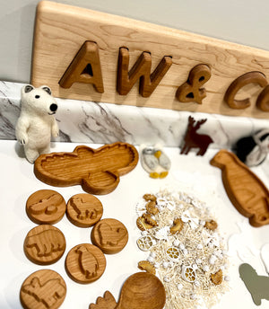 Wooden animal tokens and shapes including bear, owl, and crocodile with natural dried pasta and botanicals on white surface