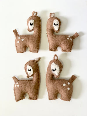 Set of four handmade felt deer figures with stitched details in brown and white on white background