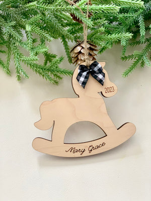 Maple plywood rocking horse ornament engraved with 2023 and personalized name hanging on pine branch