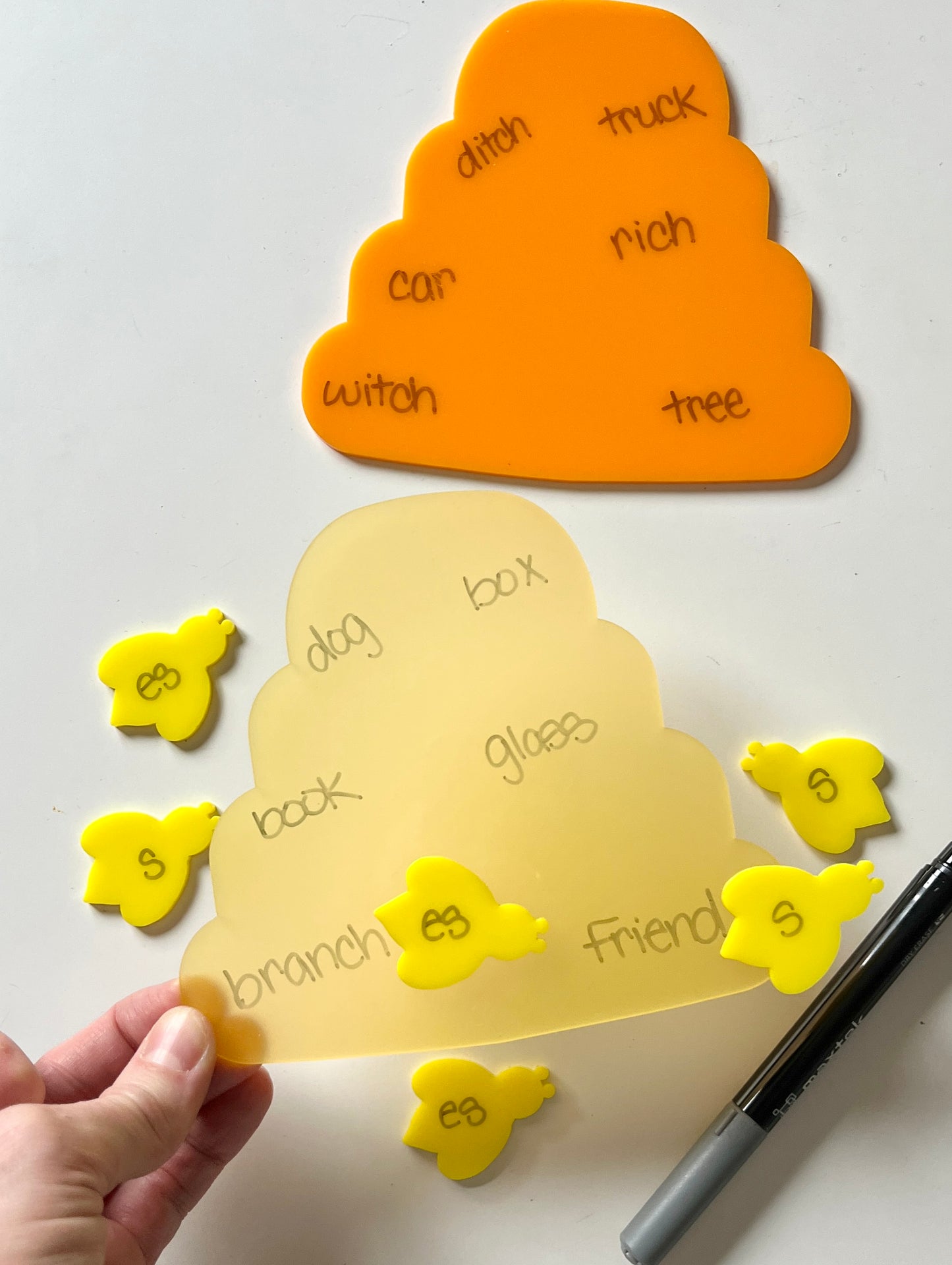 Yellow and orange bee and hive dry erase educational tools on a white background
