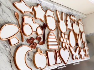 Wooden sensory trays shaped like animals, flowers, fruit, and objects with white inserts on marble surface