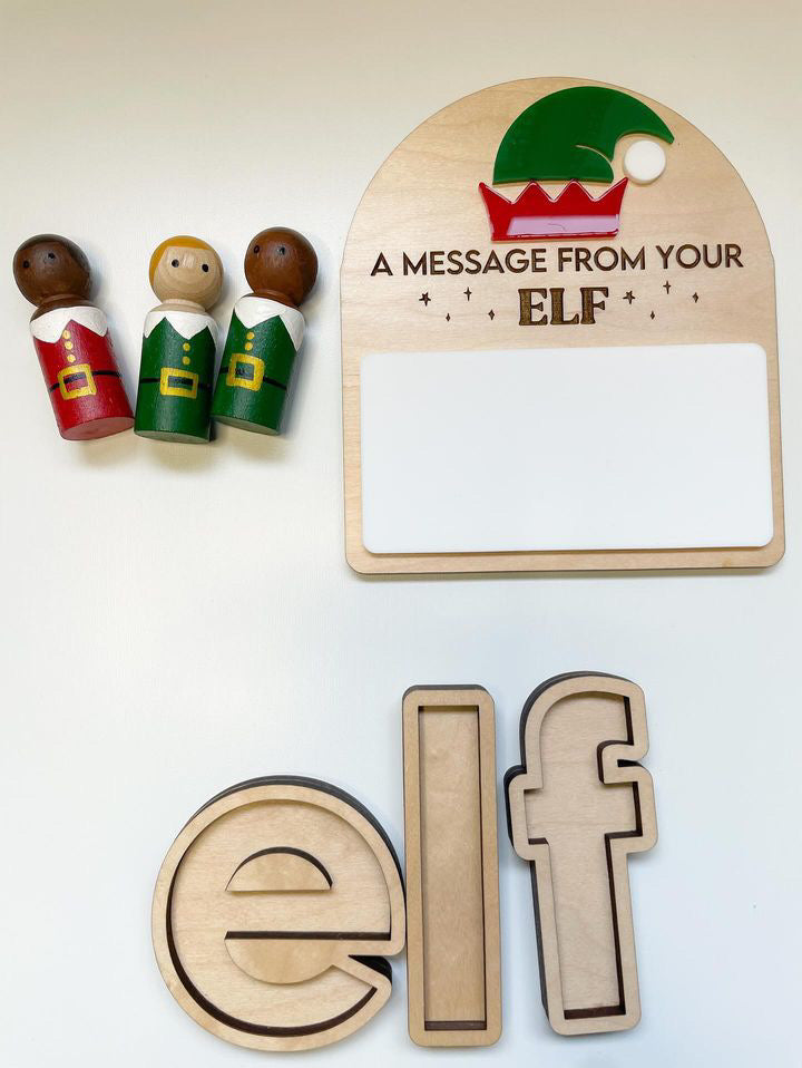 Wooden elf-themed message board with three painted elf figurines and letter-shaped wooden trays spelling "elf