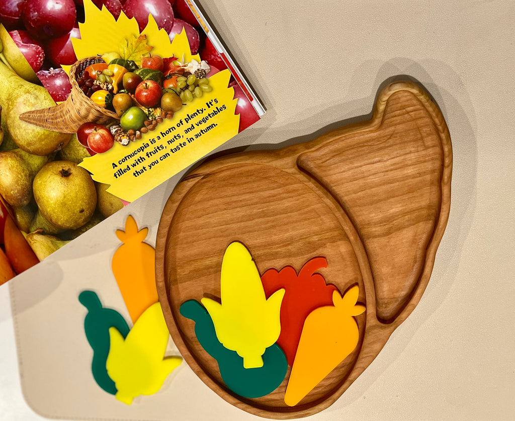 Smooth wooden tray shaped like a cornucopia with colorful foam fruits and vegetables on a beige surface