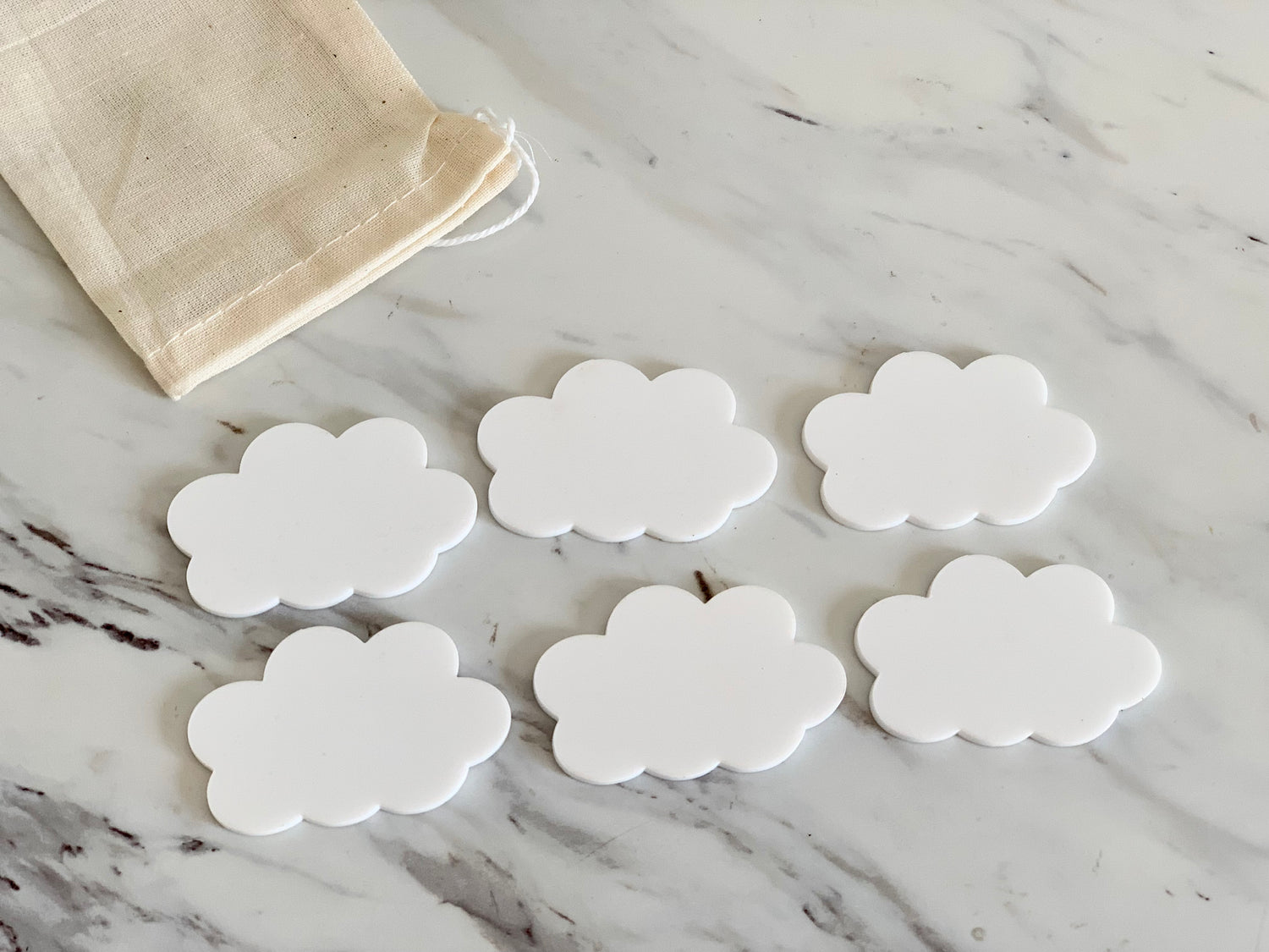 Set of six white cloud-shaped dry erase boards with rounded edges on marble surface next to a beige cloth bag