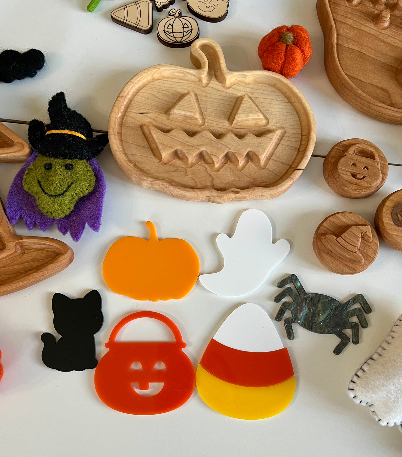 Wooden jack-o'-lantern tray surrounded by Halloween shapes including ghost, cat, candy corn, spider, and felt witch face on white background
