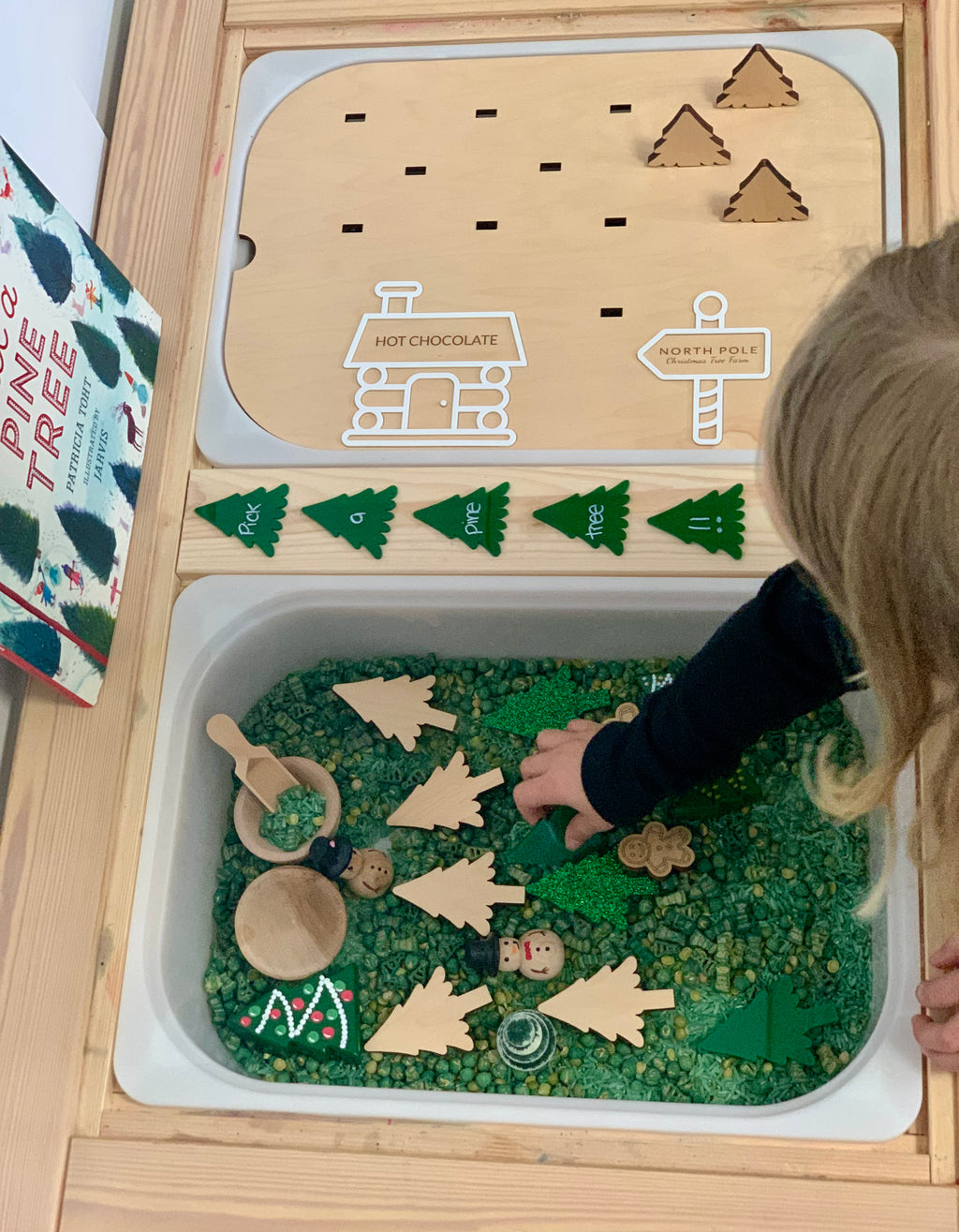 Wooden North Pole Christmas Tree Farm Flisat insert with plantable trees, green sensory base, and child playing with pieces
