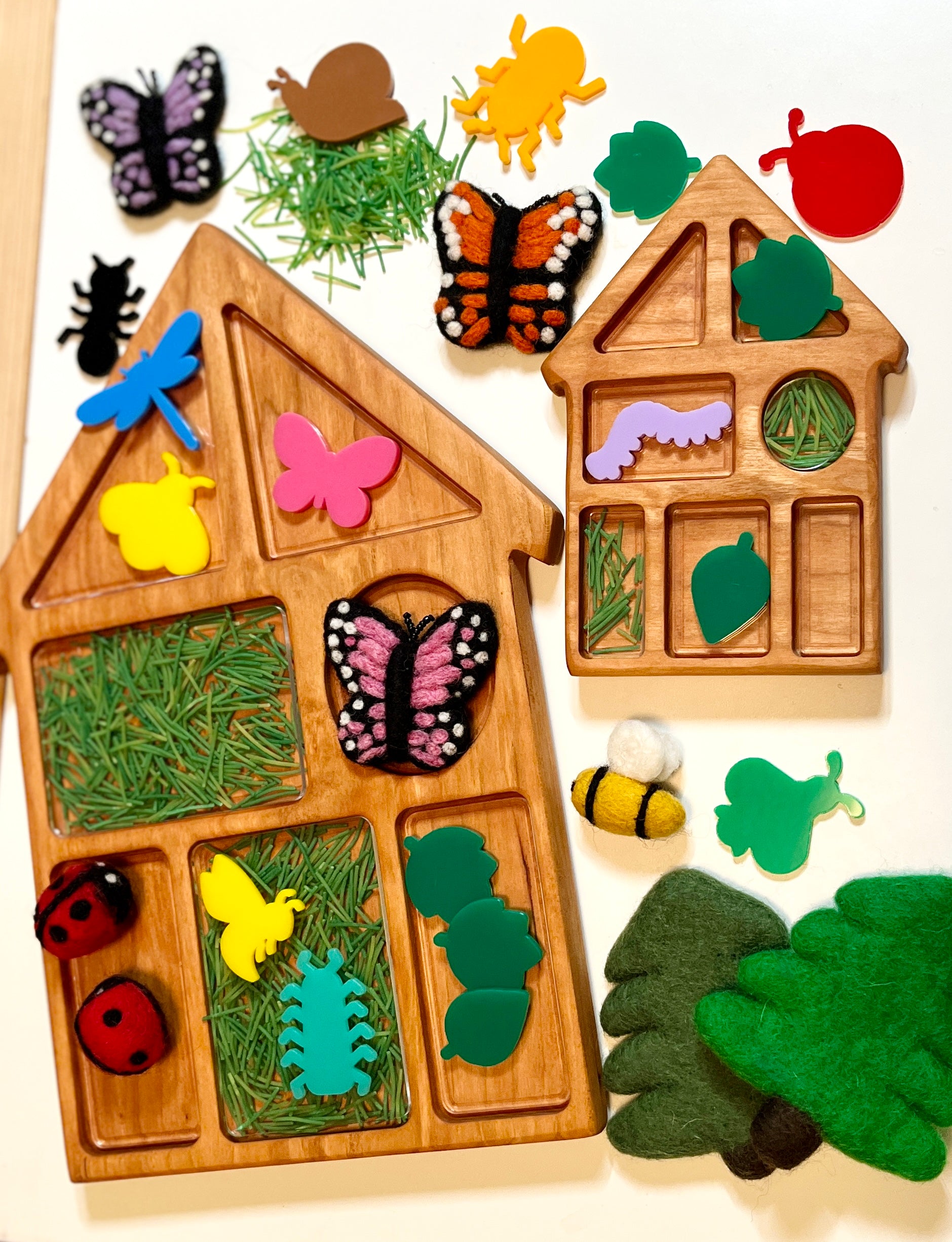 Wooden house shaped tray with compartments, with nature-themed felt and acrylic pieces including leaves, butterflies, and a bee on a light background.