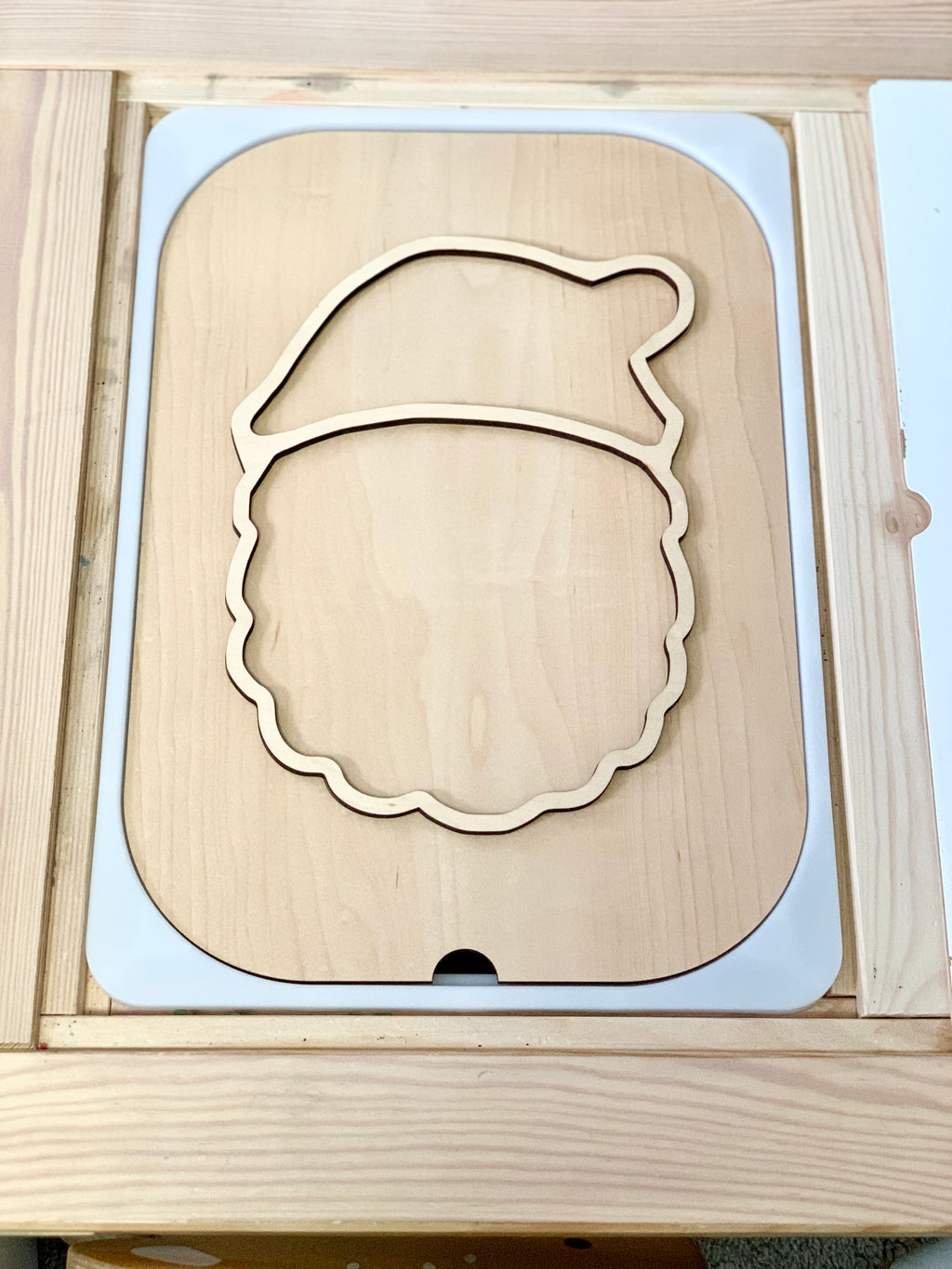 Light wood puzzle outline shaped like a Santa Claus head with a hat on a matching wooden base
