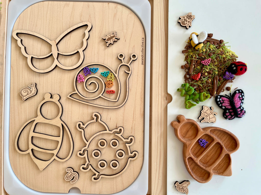 Wooden puzzle board with insect-shaped cutouts and colorful small bugs, next to a tray with dried moss and wooden insect figures